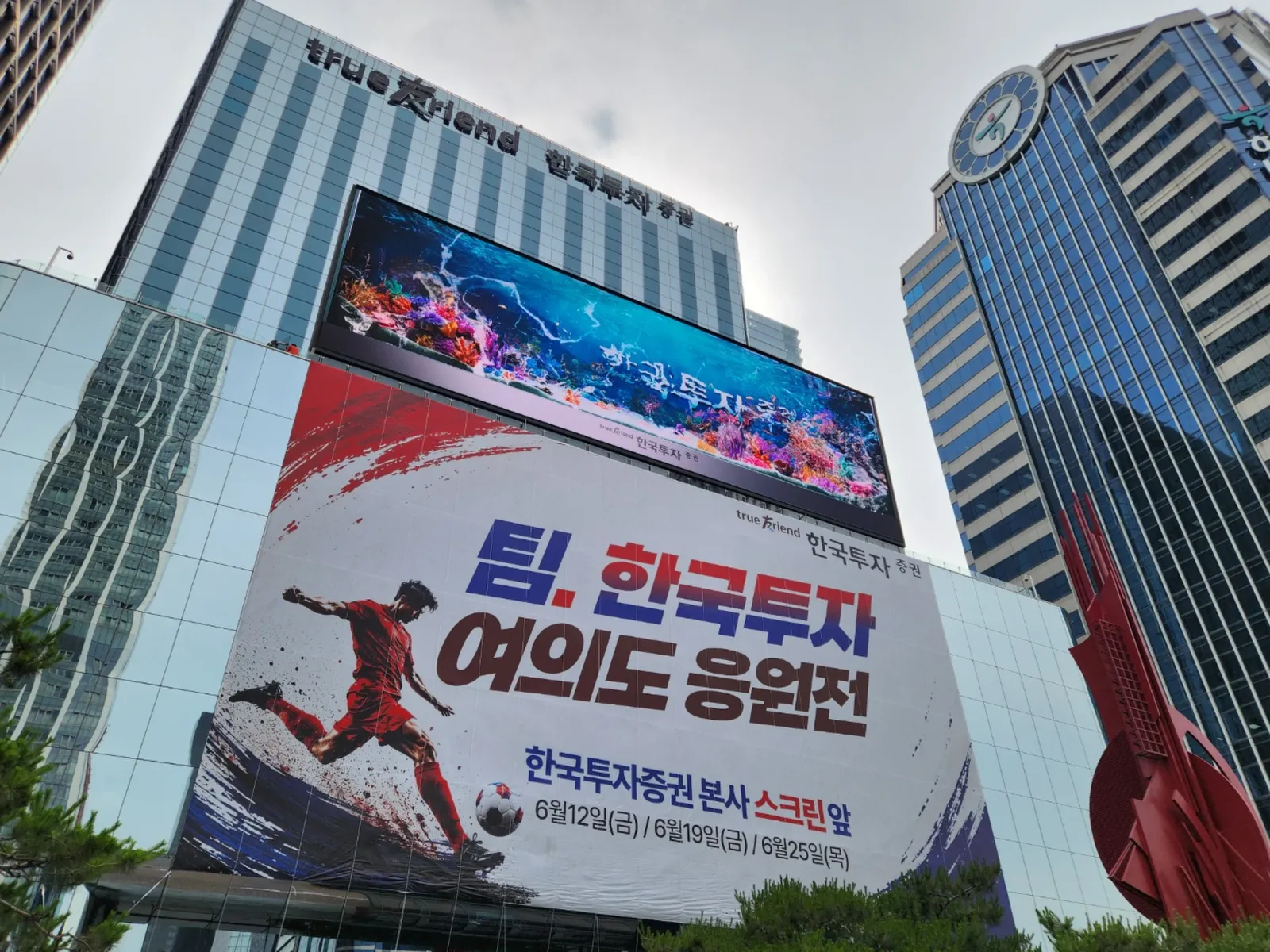 빌딩 외벽 로프 고공 현수막 설치 현장, 주변 조경과 함께 촬영된 시공 사례